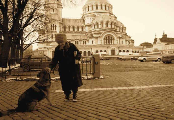 An old woman patting her dog outside the Alexander Nevsky Cathedral in Sofia Bulgaria